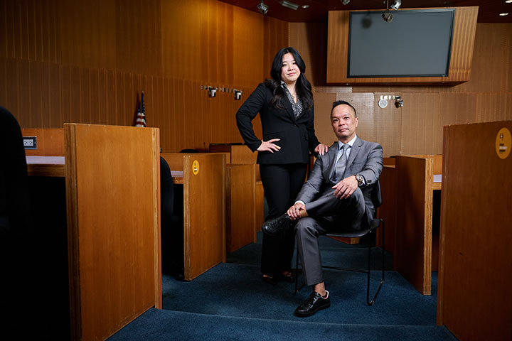 Two people in professional attire standing in a courtroom environment